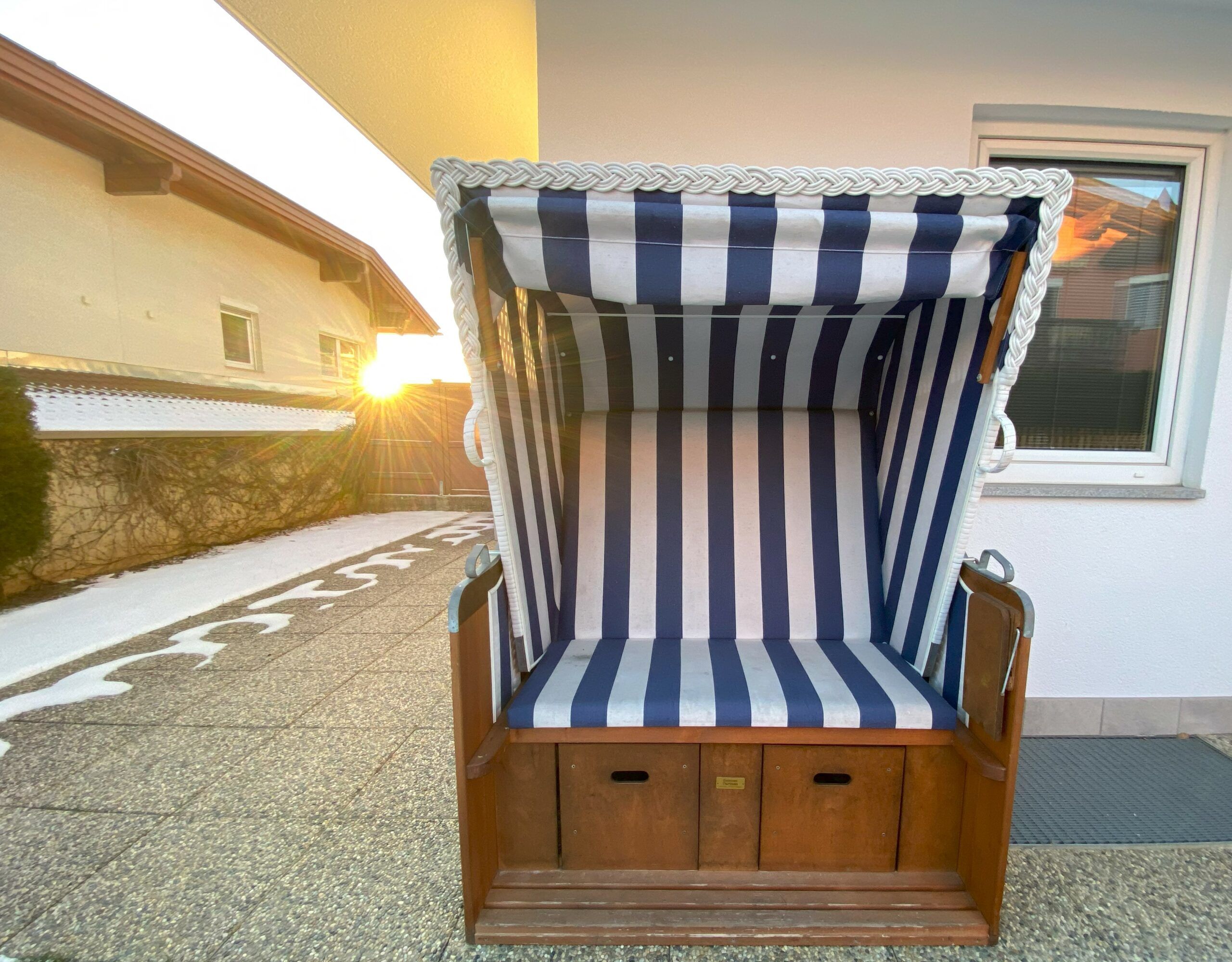 Zu den Annehmlichkeiten der Ferienwohnung Anna-Lena gehört ein Liegestuhl aus Holz mit blau-weißen Streifen.