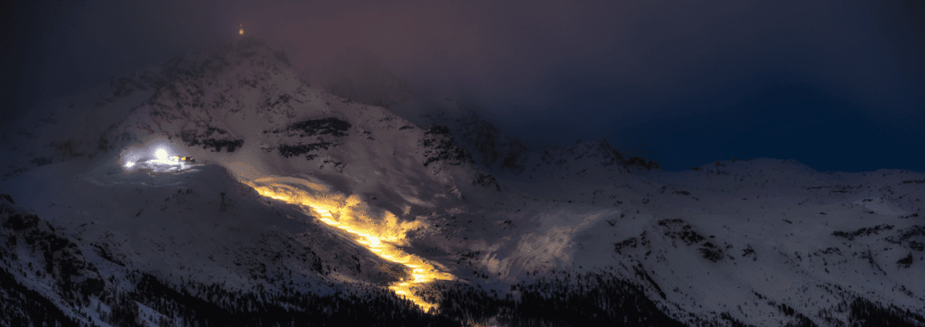 Ein schneebedeckter Berg, auf den beim Nachtskilauf im Zillertal ein Licht scheint.
