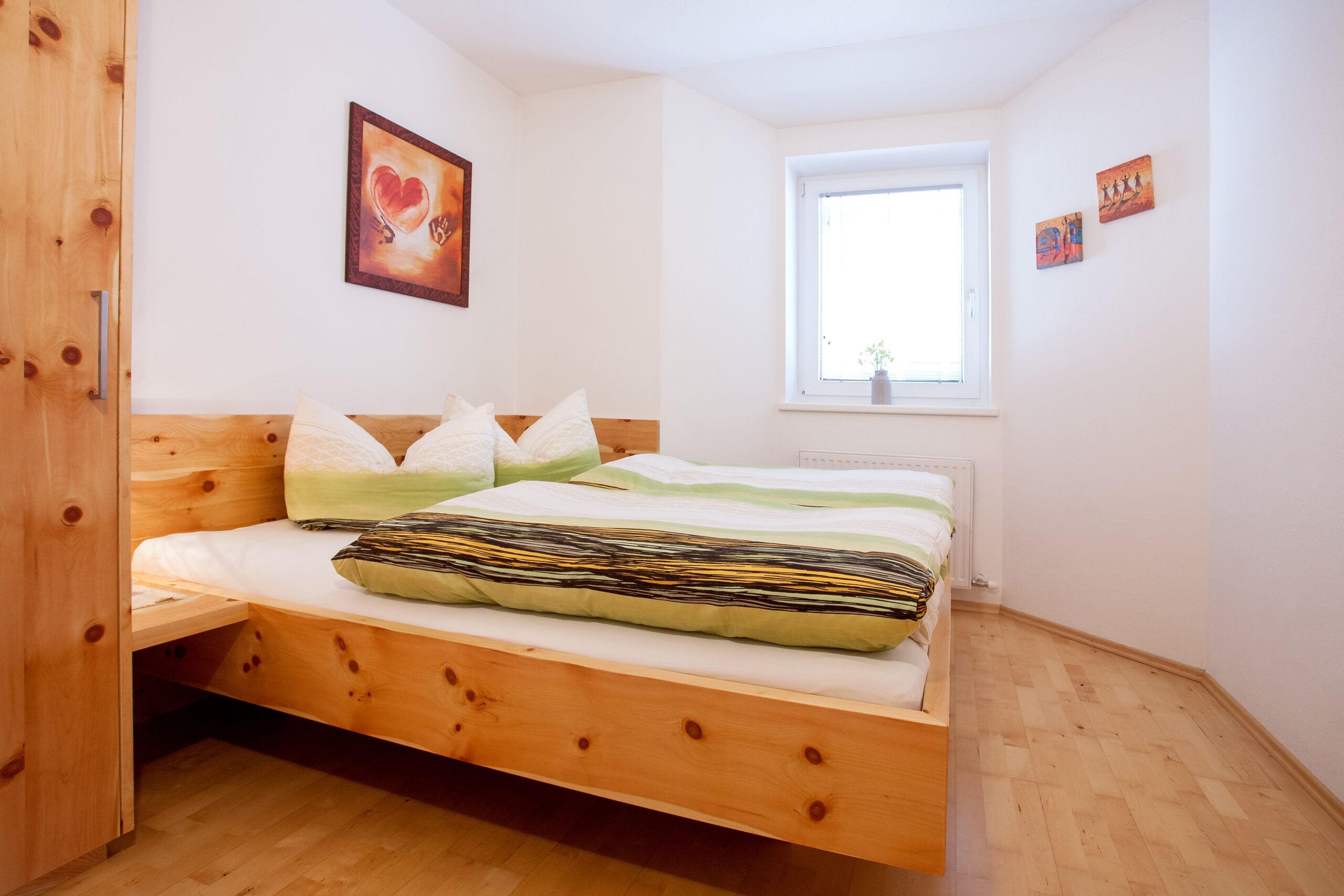 Ein kleines Schlafzimmer mit einem Holzbett und einem Fenster.